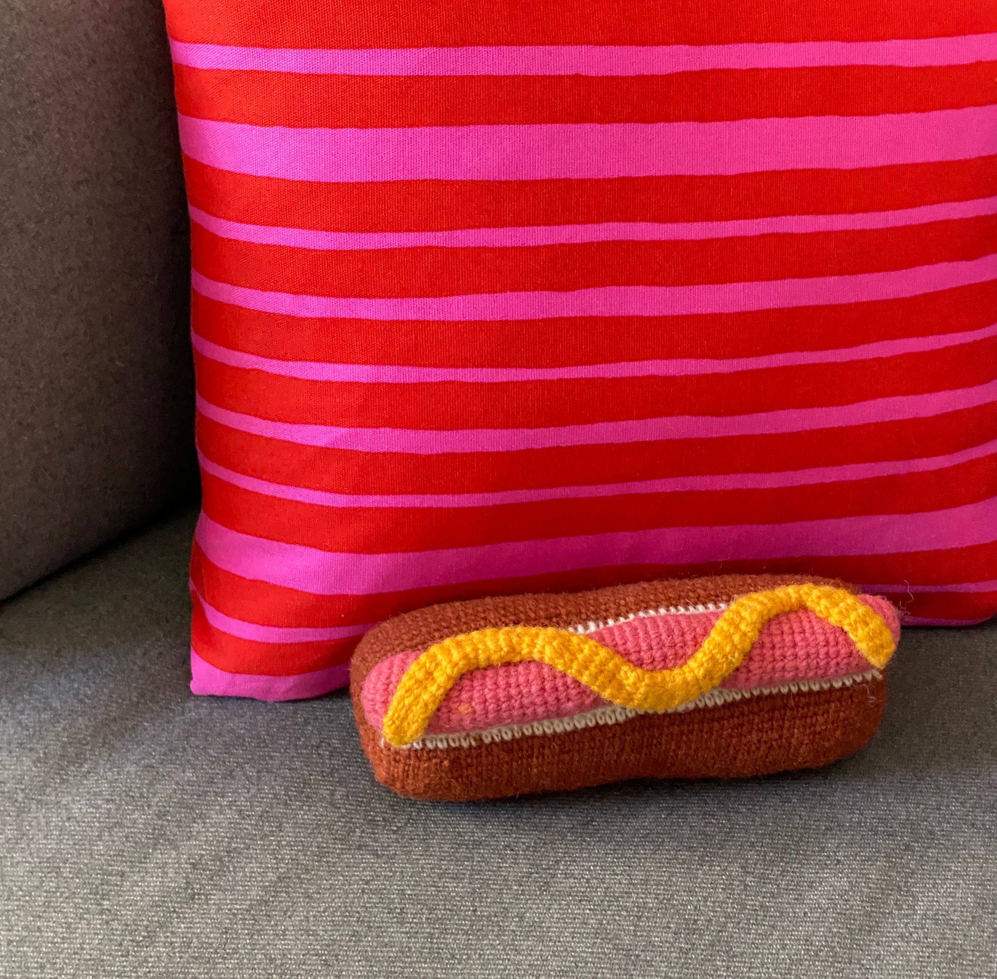 Crocheted hot dog resting against a pillow