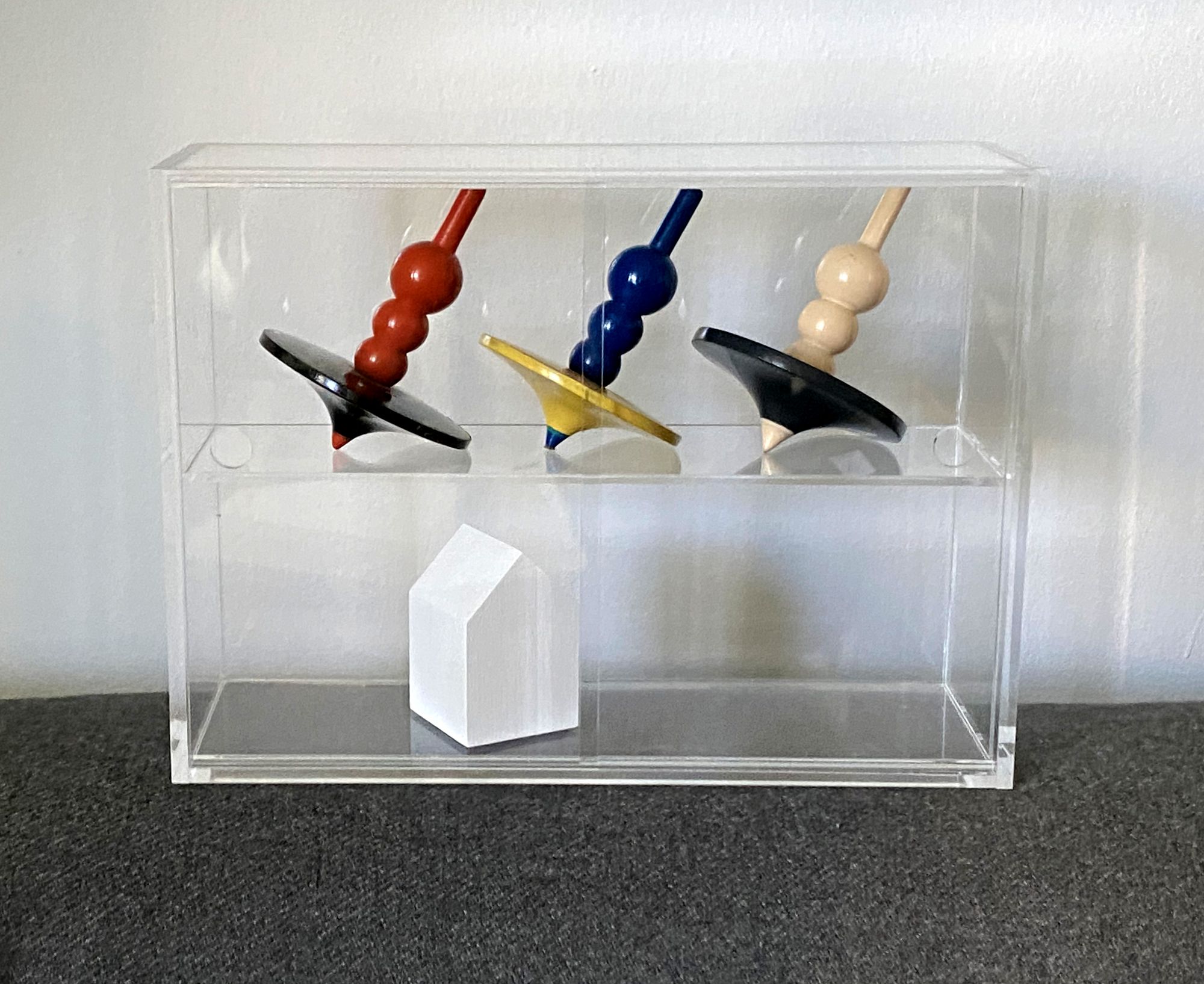 Acrylic display case with three tops on the upper shelf and a small White House on the bottom shelf