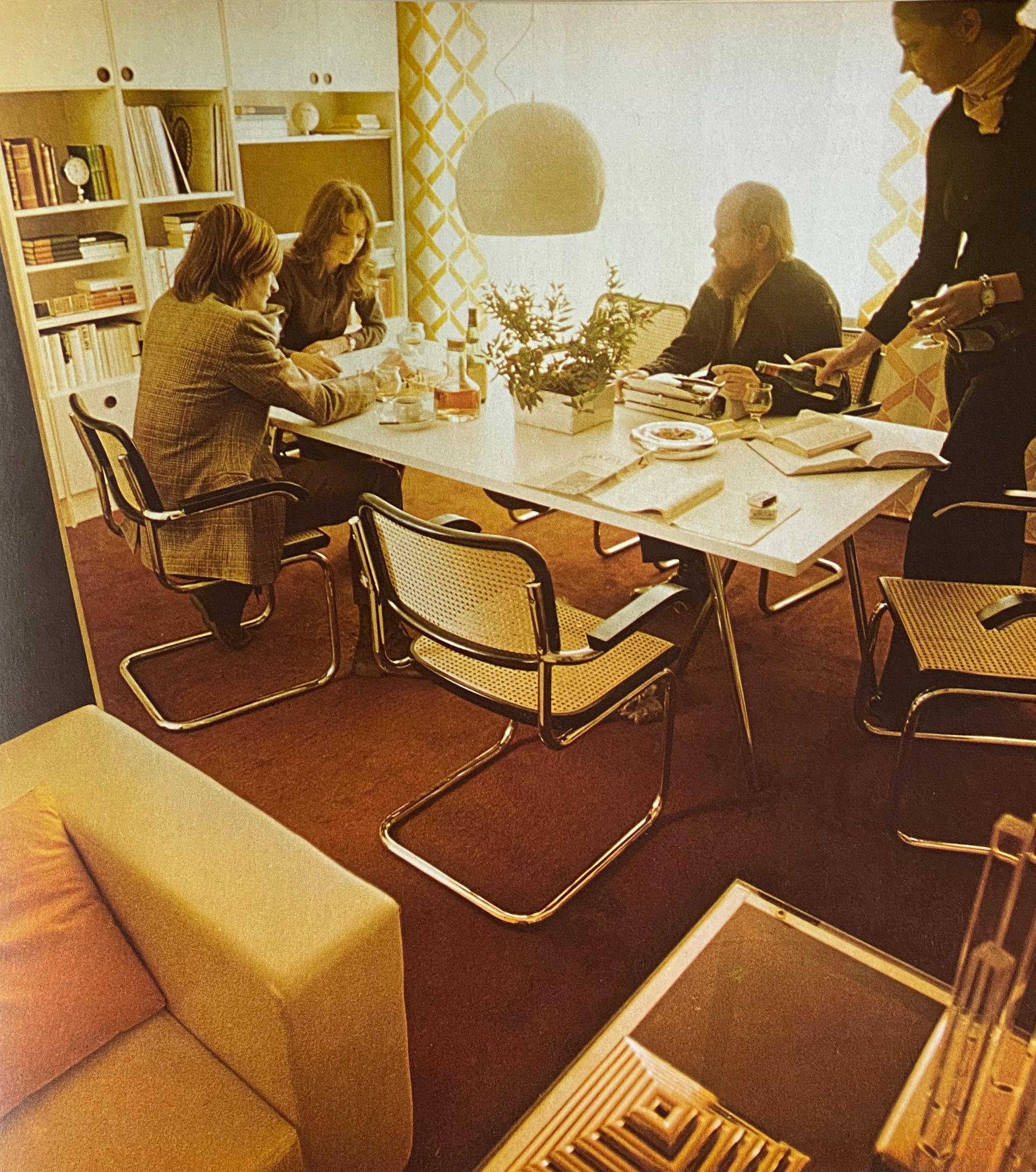 Four people gathered around a dining room table with six Cesca chairs as seating.