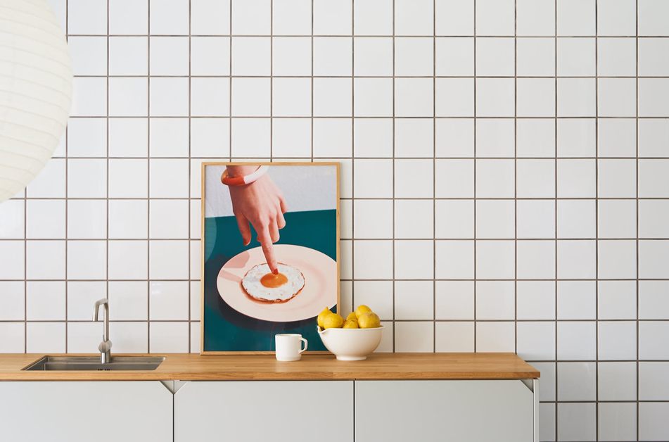 Poster propped on a kitchen counter showing a hand pointing downward at the yolk of a fried egg on.a plate