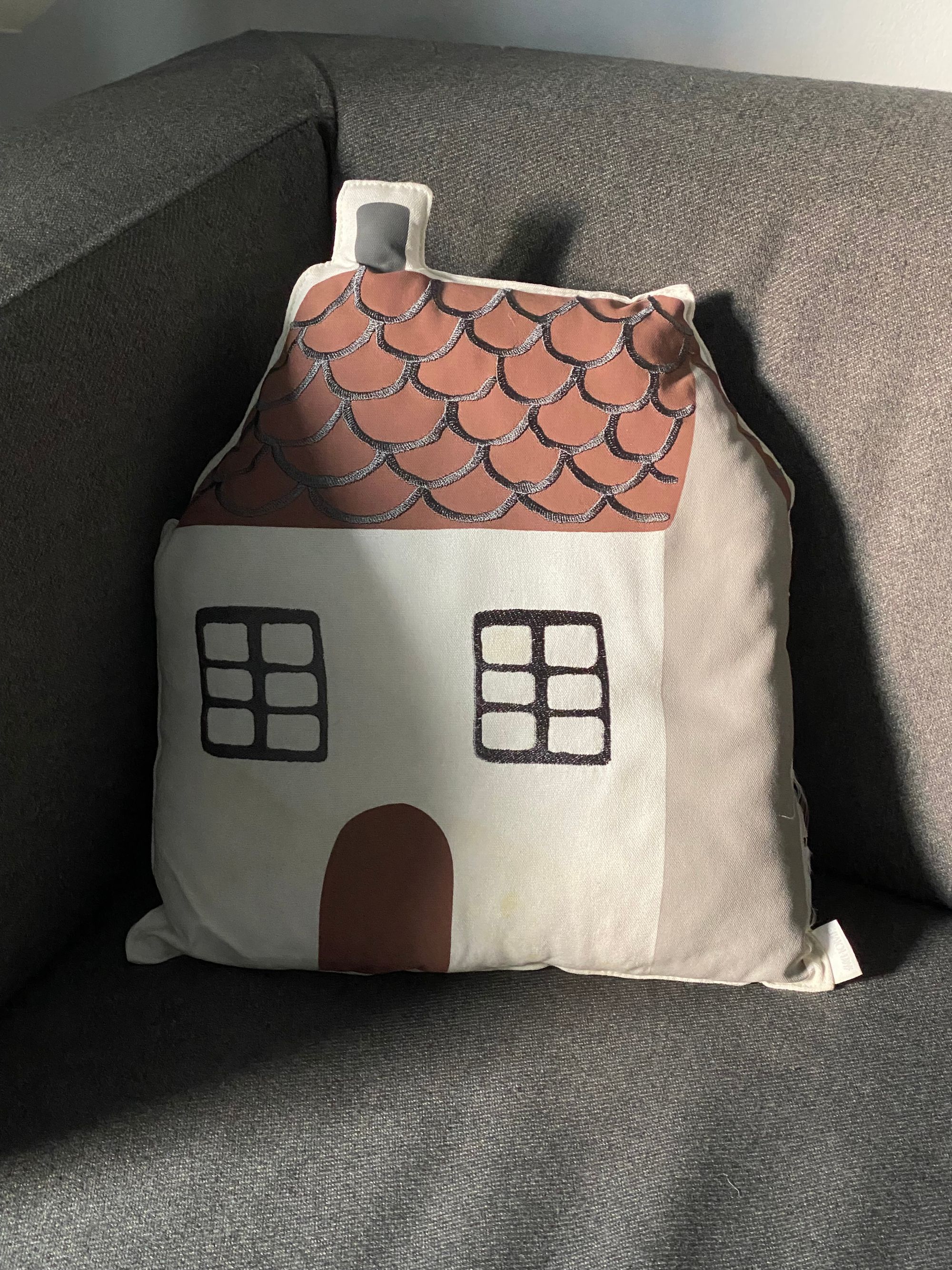 House-shaped pillow on a gray armchair.