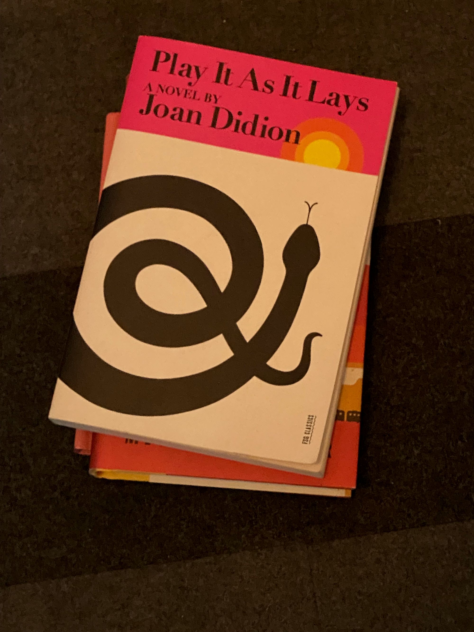 "Play It As It Lays" by Joan Didion on a carpeted floor.