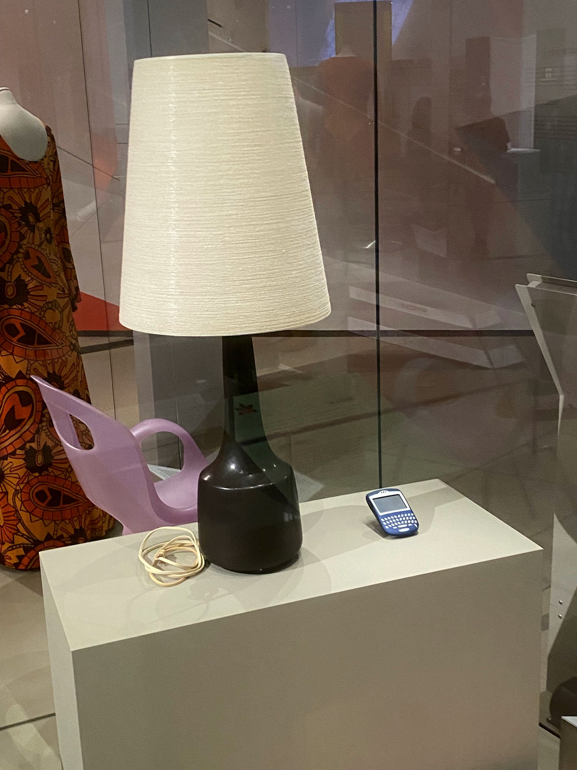 Tall table lamp beside a small BlackBerry device.