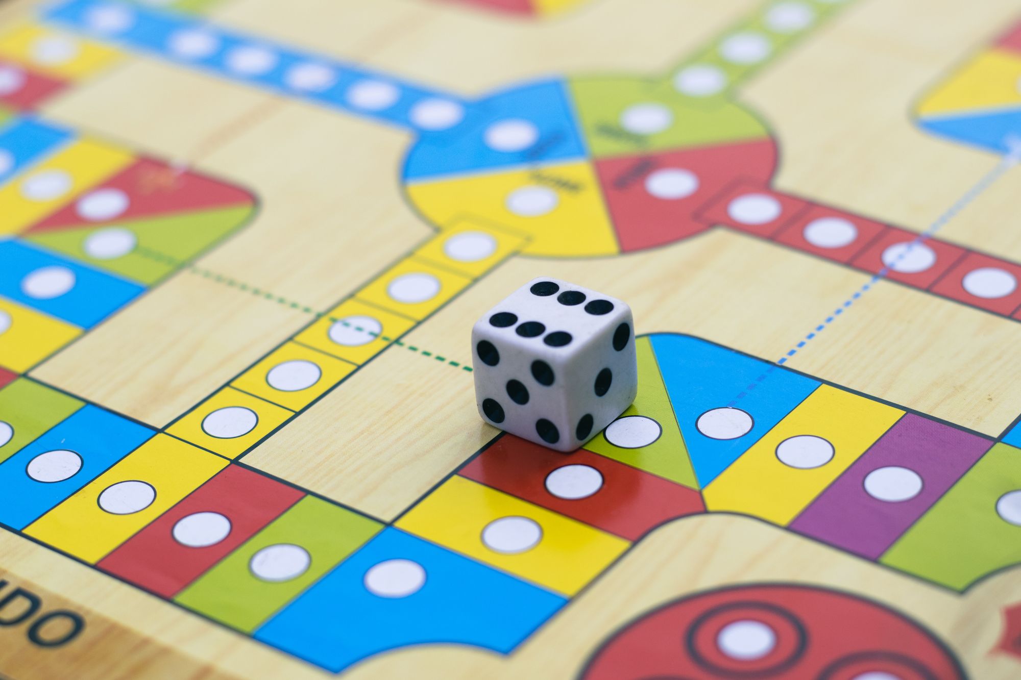 A colourful board game surface with a black and white die resting on it.