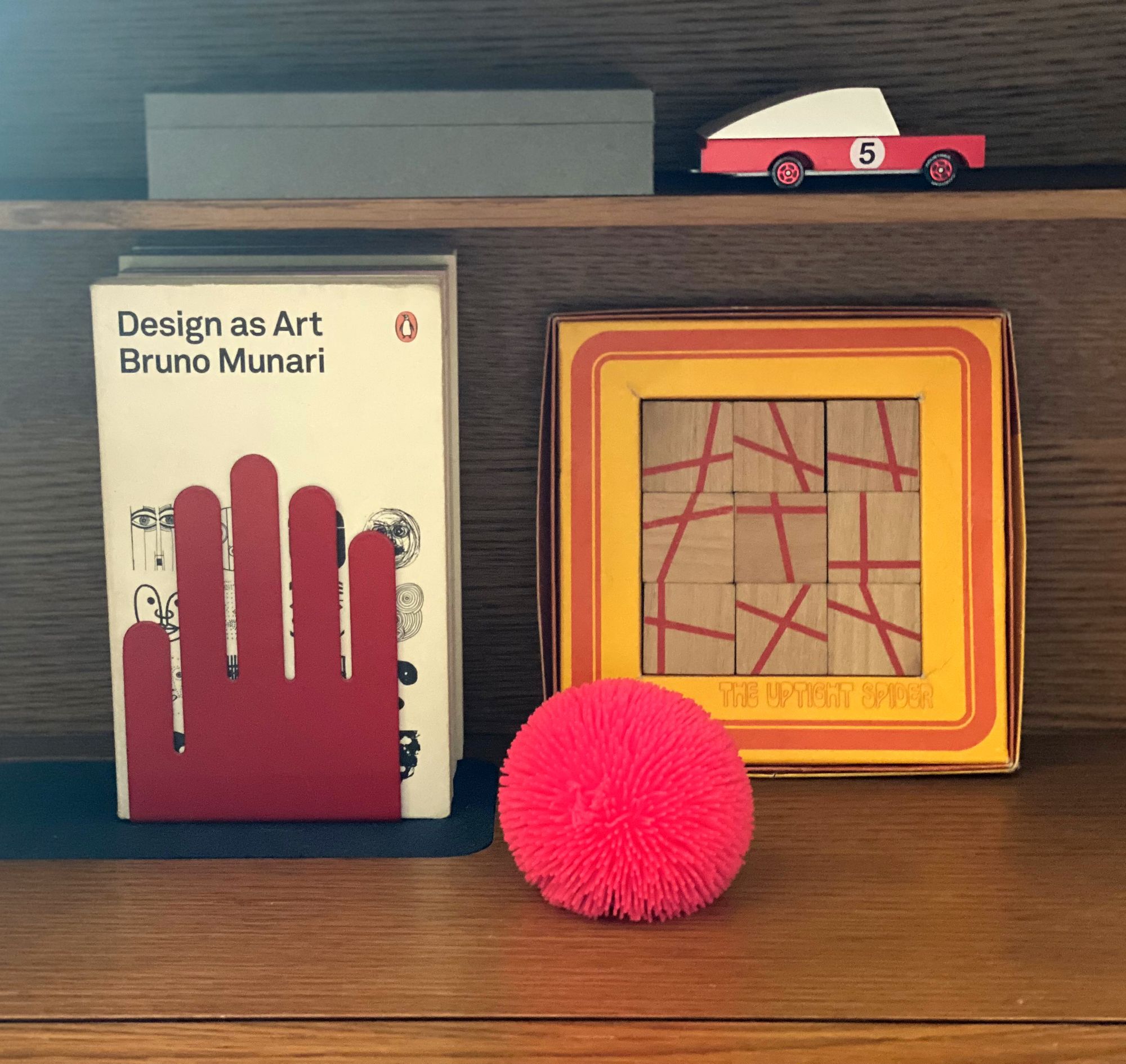 Assorted items on a desktop, including a toy sportscar and a hot pink stress reliever ball.