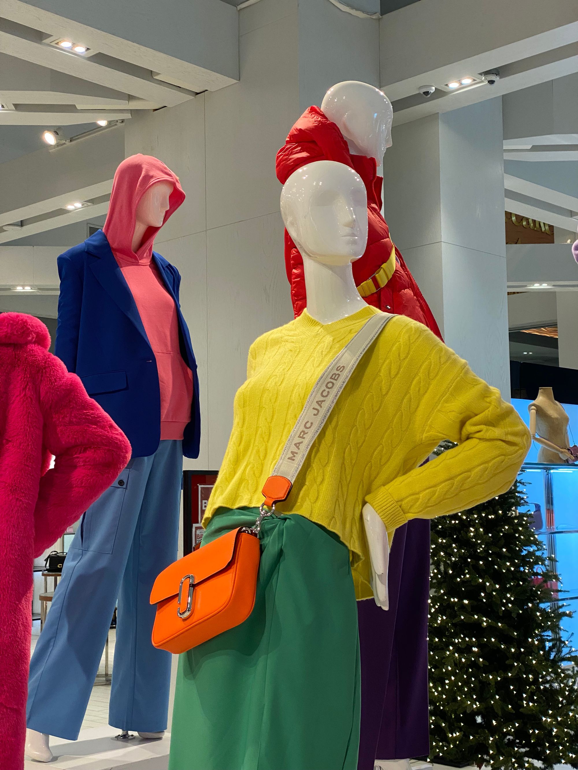 Four mannequins wearing very bright items of clothing.