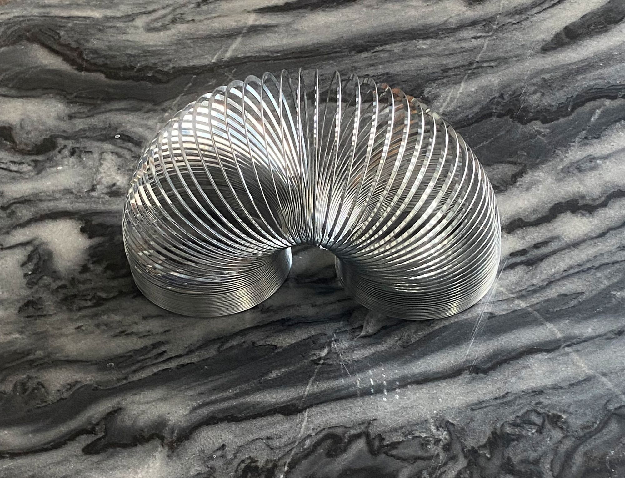 Slinky resting on a marble tabletop in shades of grey.