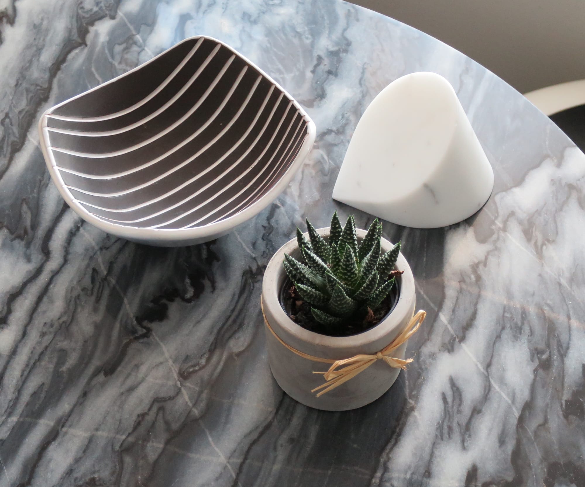 Bowl, paperweight, and succulent on a grey marble tabletop.