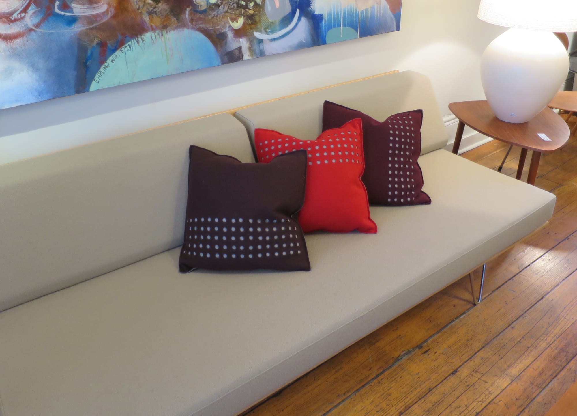 Three Bev Hisey cushions on a modern sofa.