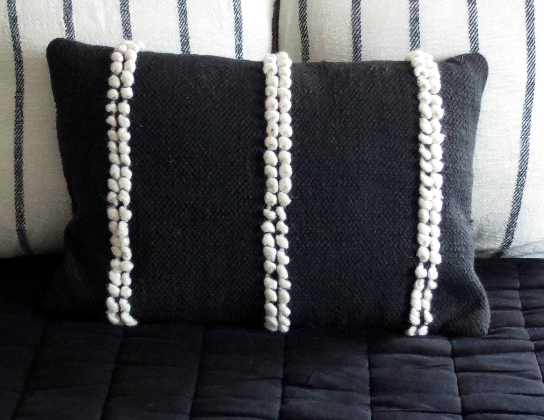 Black and white decorative pillows on a black bedspread.