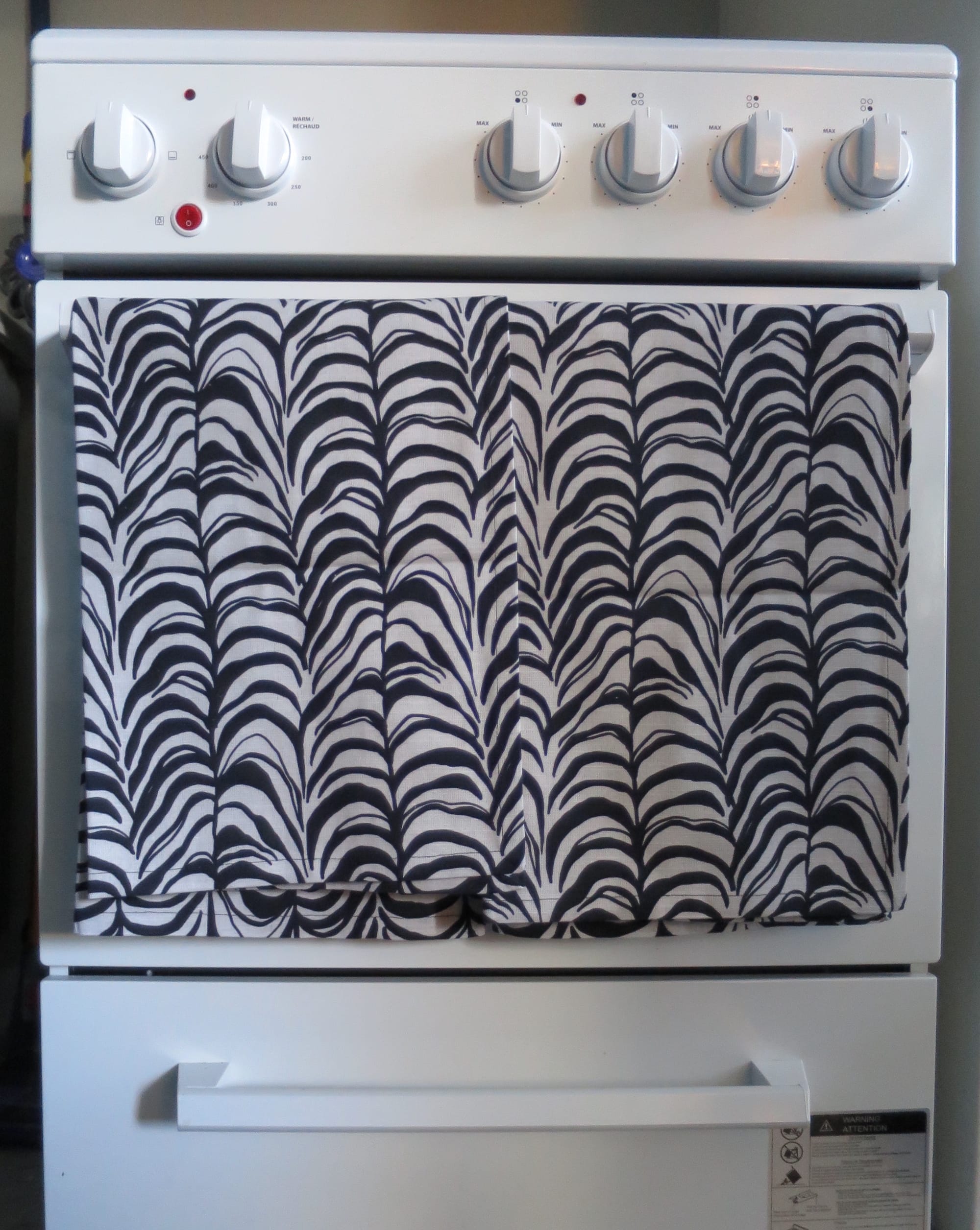 Two tea towels hanging on an oven door handle.