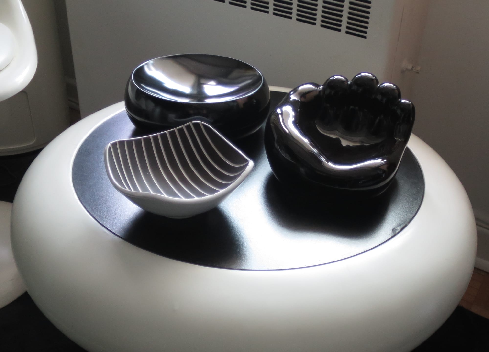 Three black bowls of various shapes on a space age black and white side table.