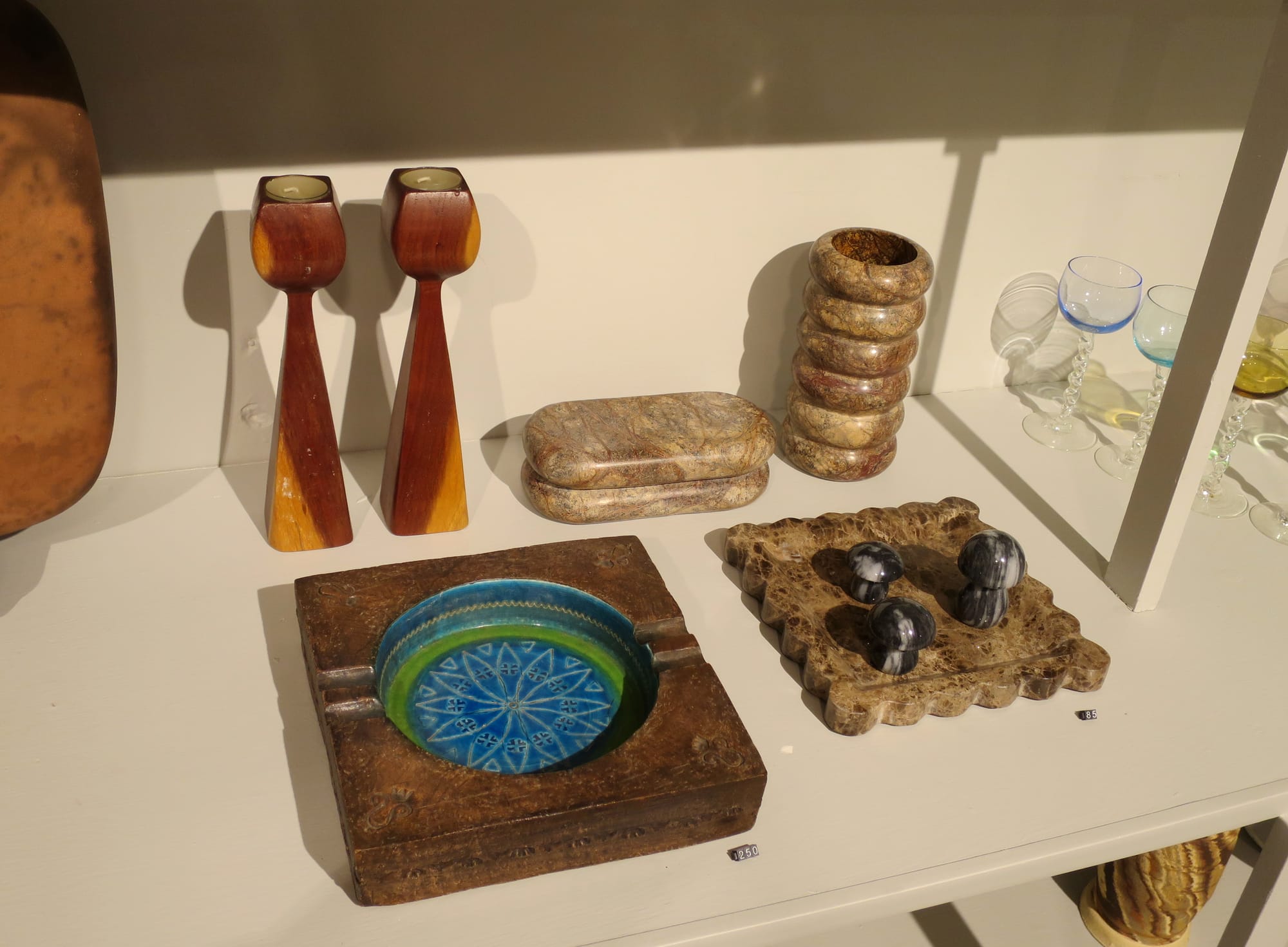 An ashtray, a pair of candlesticks and other decorative objects on a shelf.