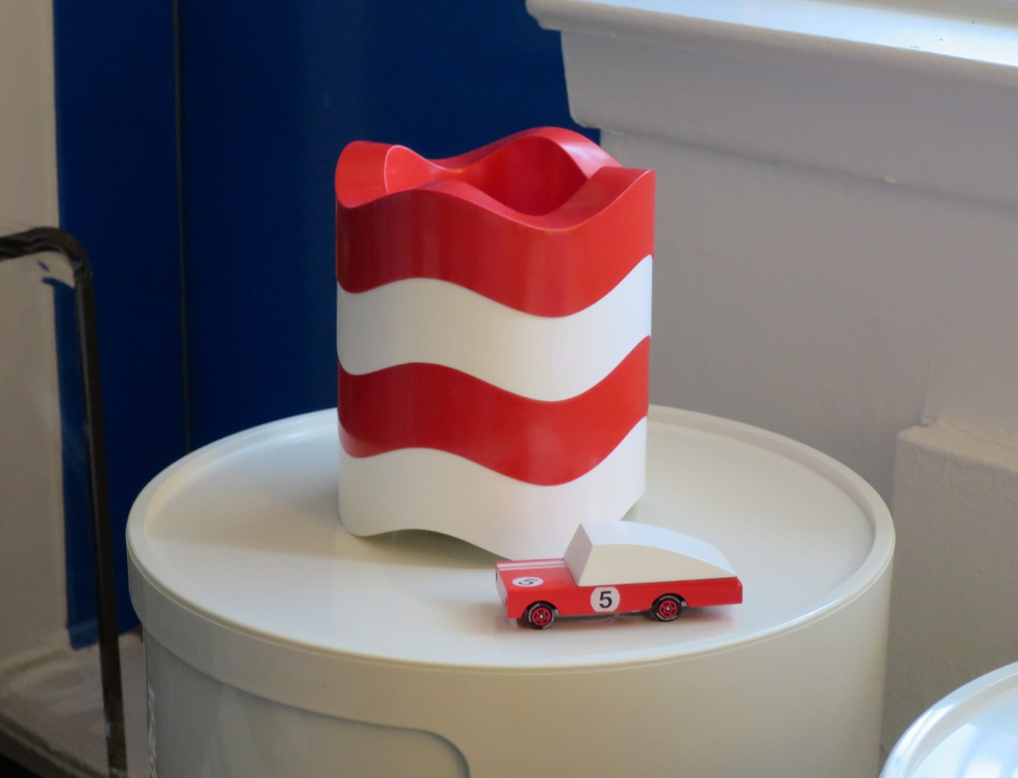 Toy red sports car displayed next to some stacking ashtrays.