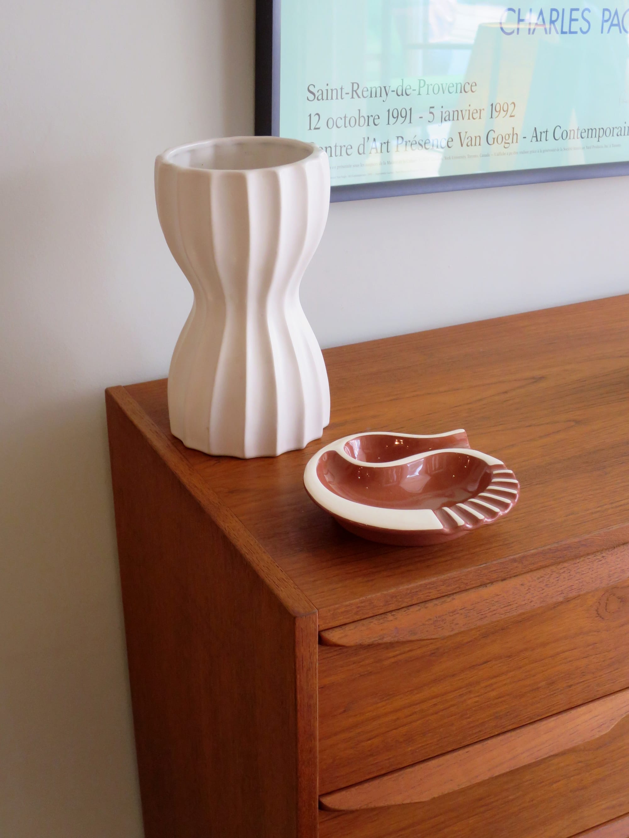 Vase and ashtray on the surface of a teak dresser.