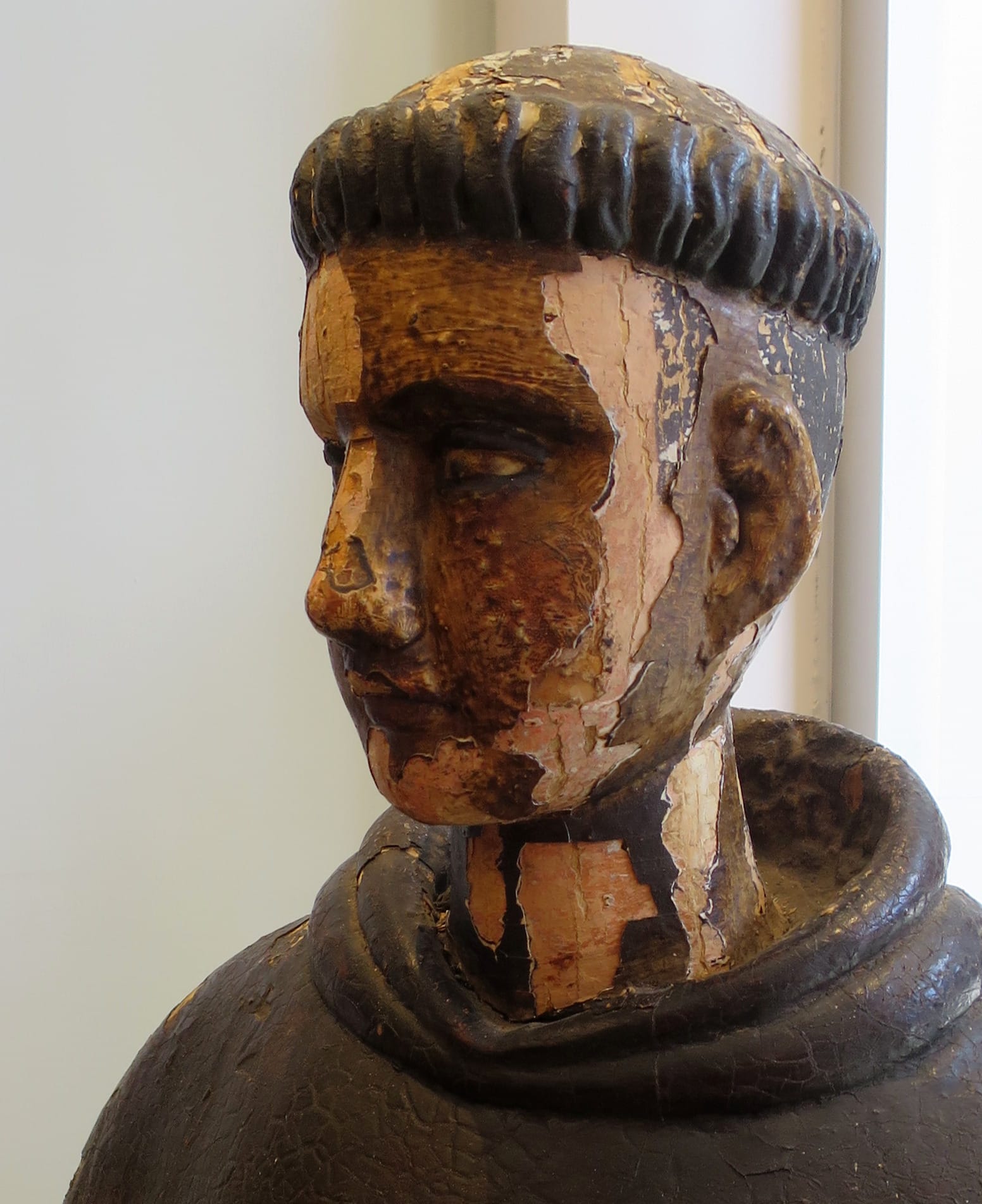 Head of a monk statue, the painted surface flaking away