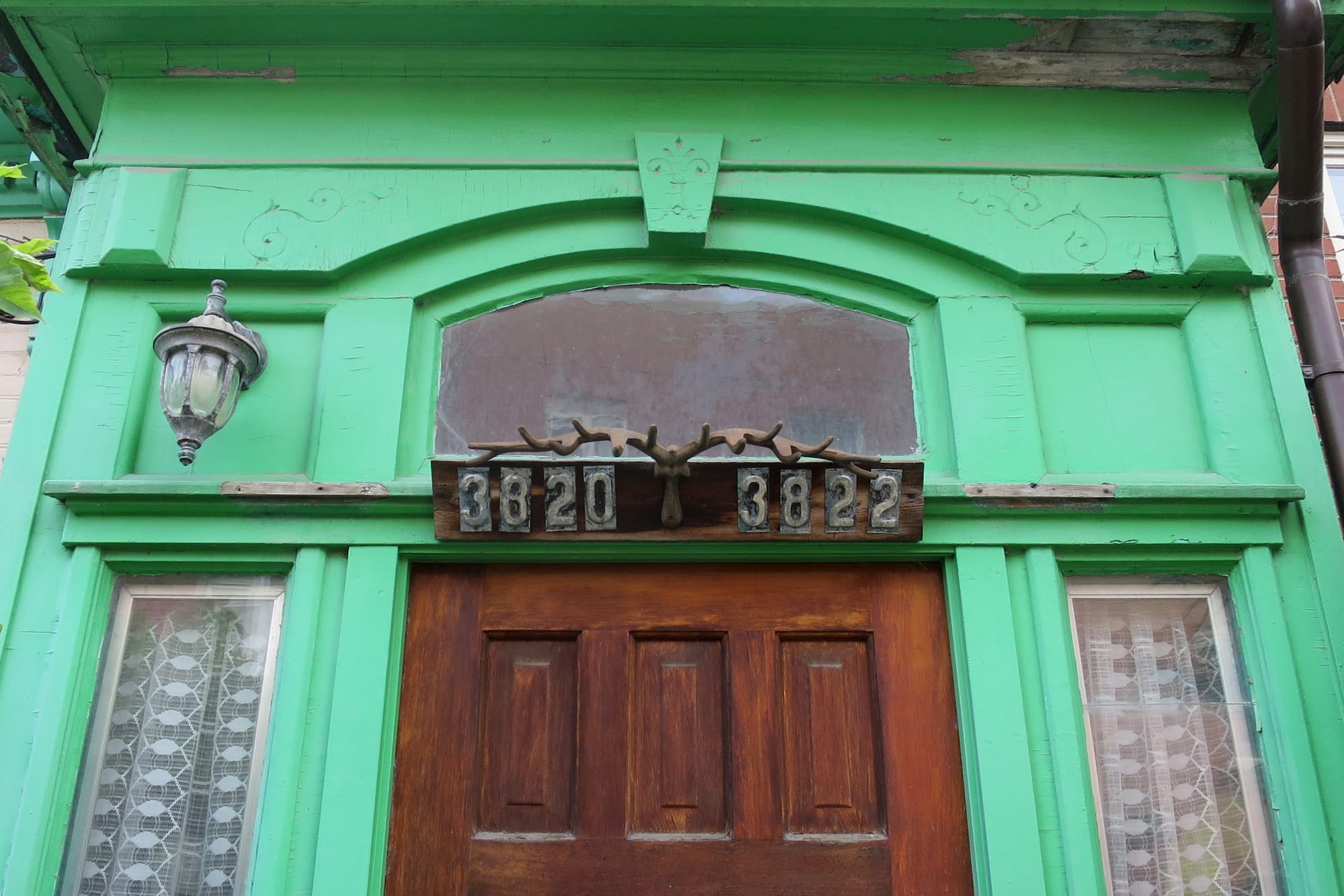 Entrance with two street numbers above the door and a brass pair of antlers mounted between them.