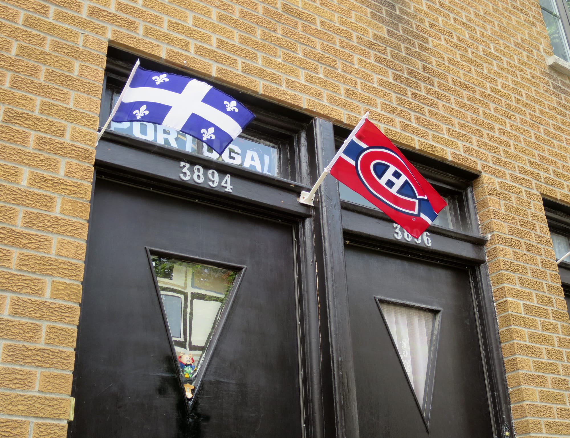 A pair of entrances, one with two flags (the Quebec flag and the flag for the Montreal Canadiens hockey team) as well as a Portugal sign.