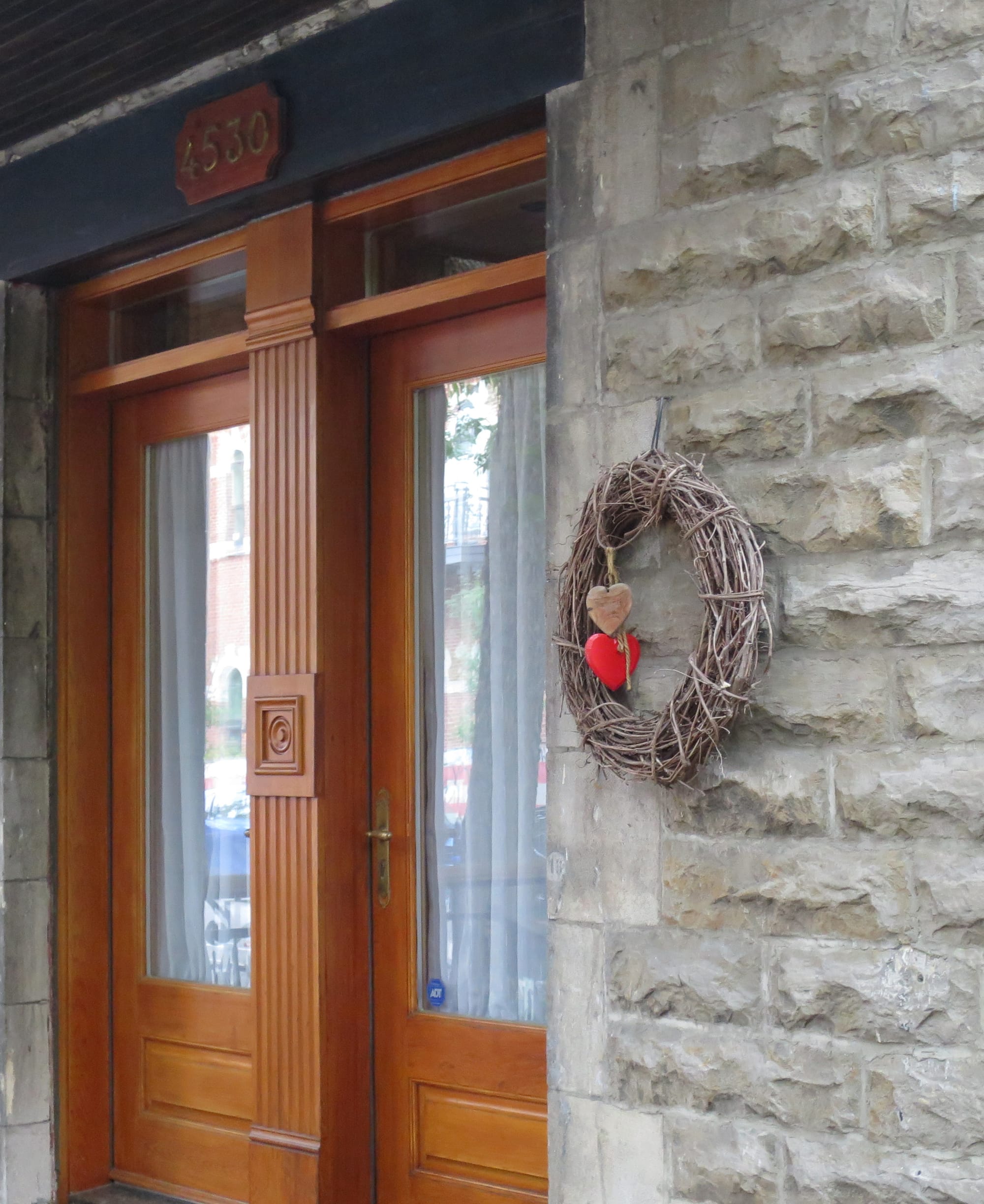 Wreath with two wooden hearts next to a pair of doorways.