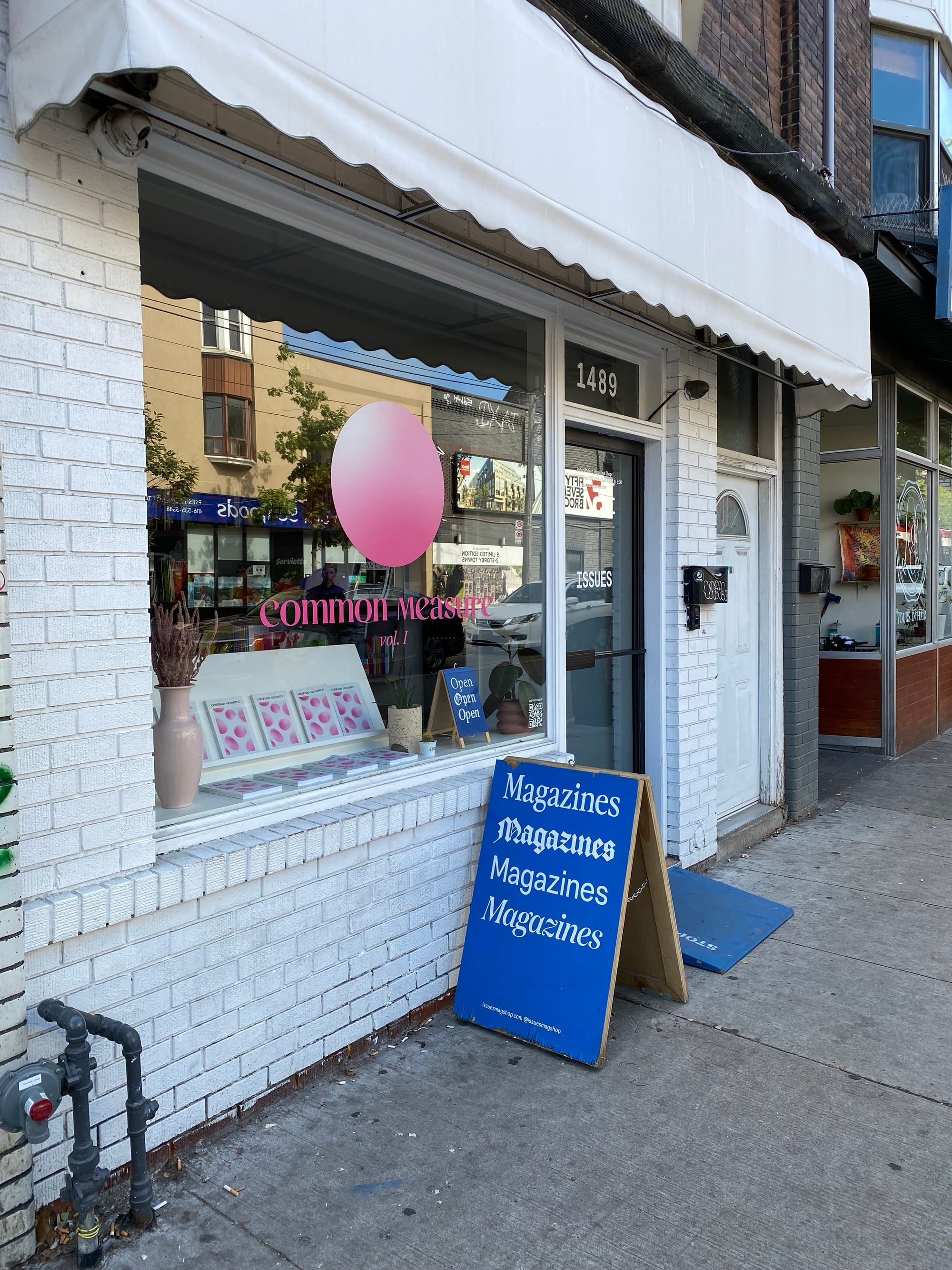 Exterior of Issues, with a signboard featuring the word Magazines repeated in several different typefaces.