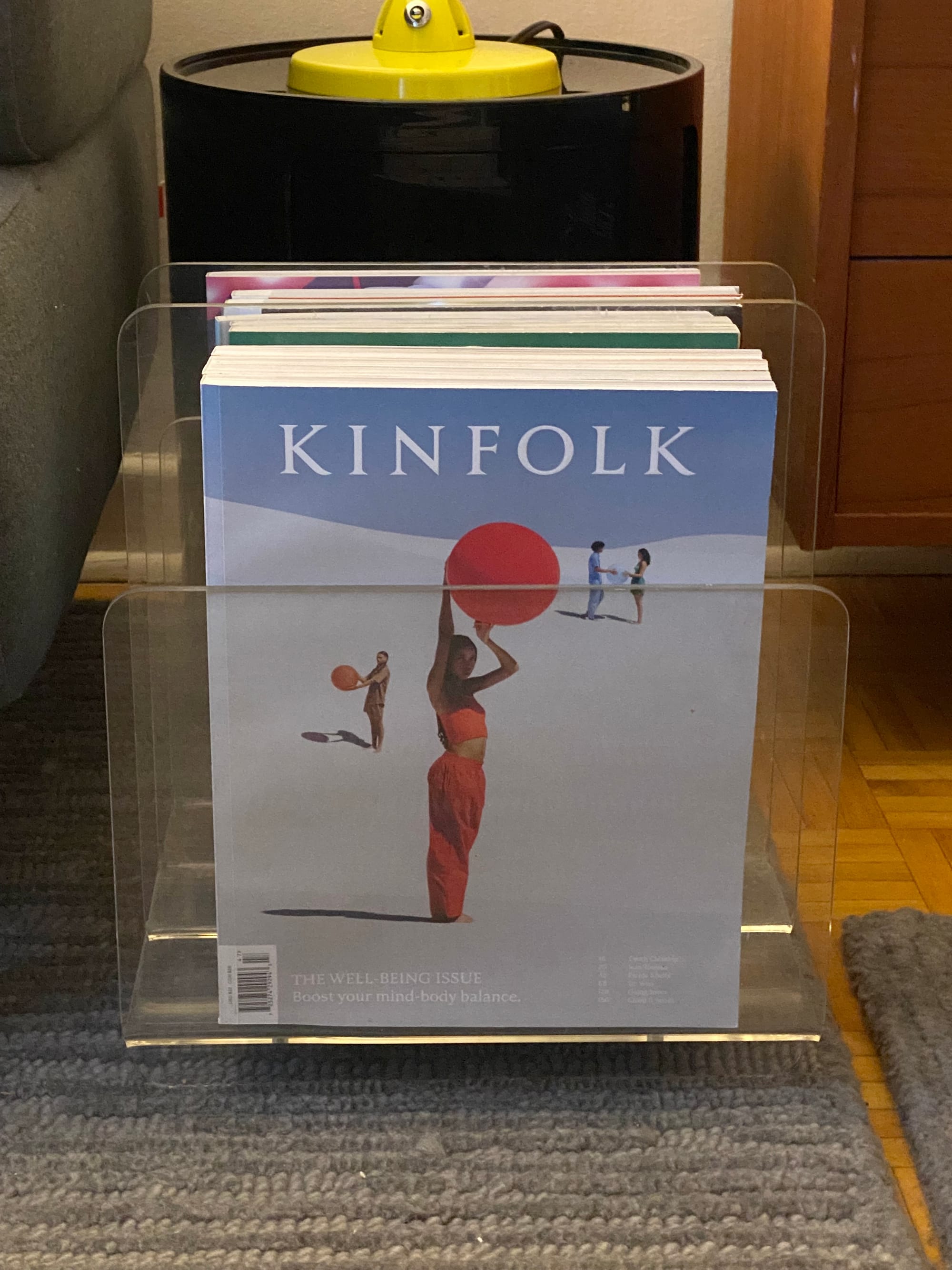 Kinfolk magazine and lots of magazines behind it, all in a Lucite magazine rack.