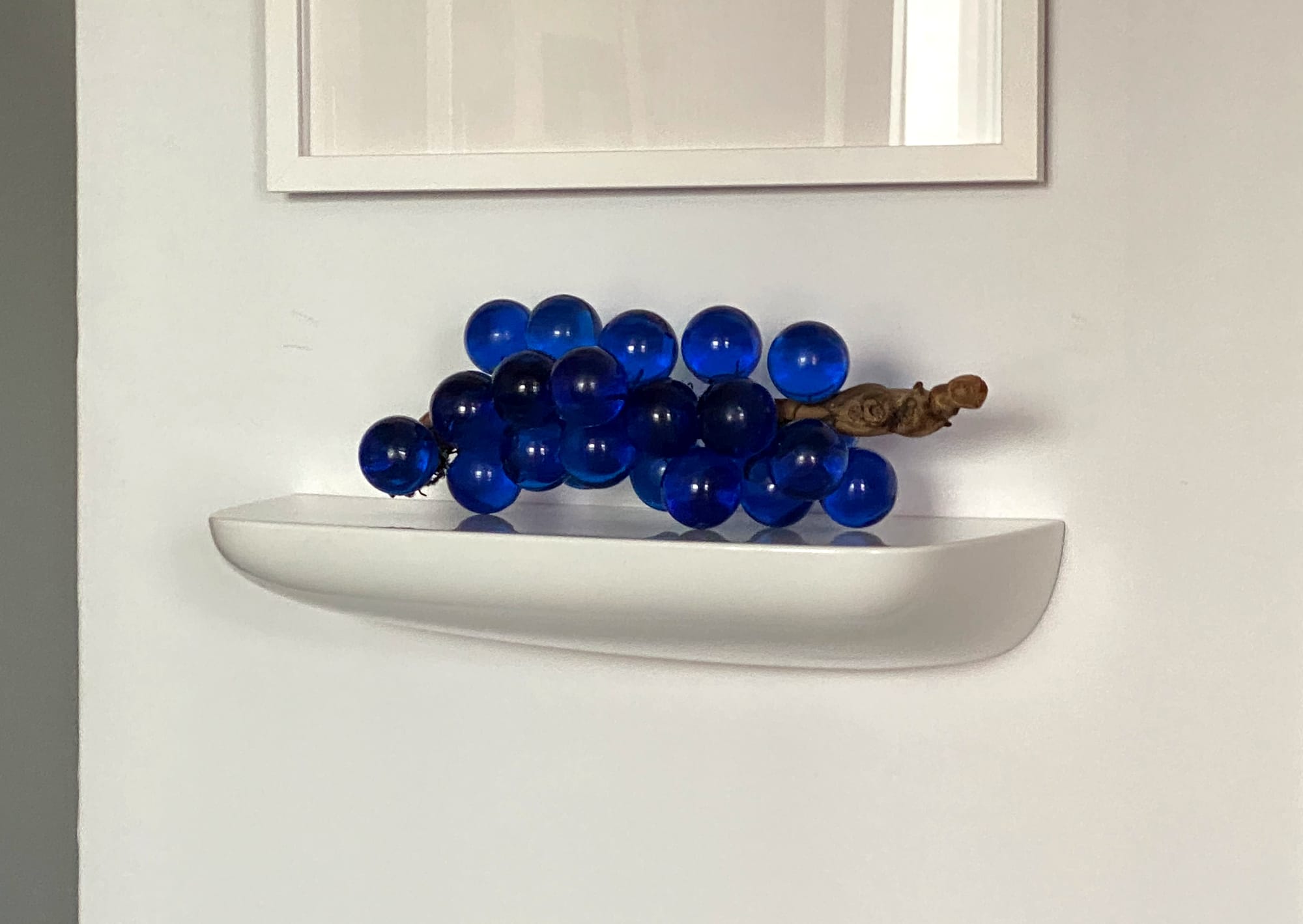 Lucite grapes on a wall shelf