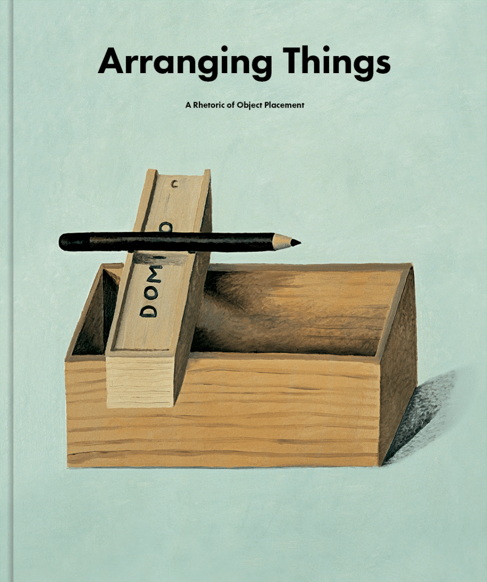 The cover of "Arranging Things" with a painting of a wooden box, domino case and pencil stacked on top of one another.