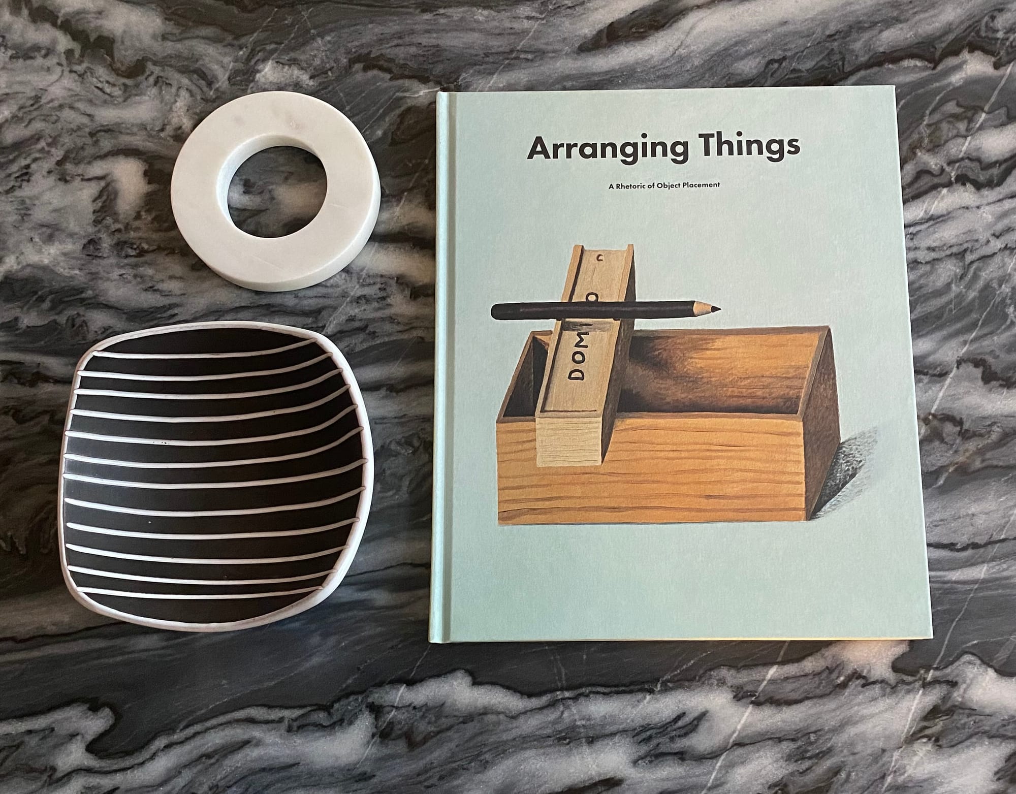 My copy of "Arranging Things" on a marble tabletop, arranged with a bowl and paperweight.