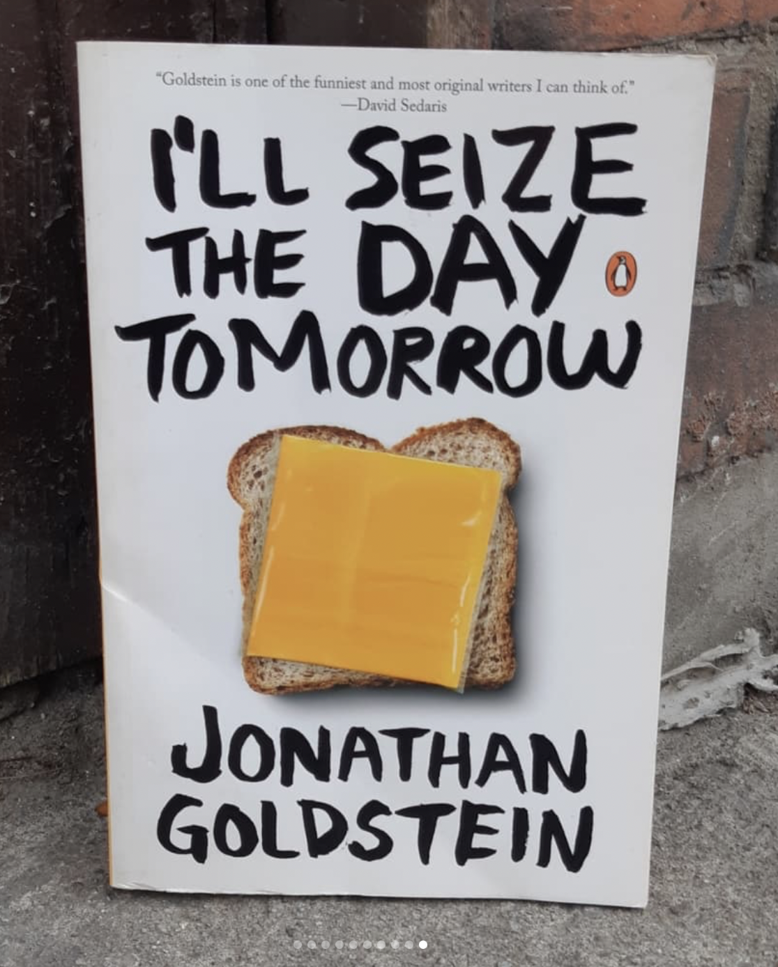 Cover of "I'll Seize The Day Tomorrow" featuring a piece of bread with a wrapped cheese slice on top, angled in relation to the bread.