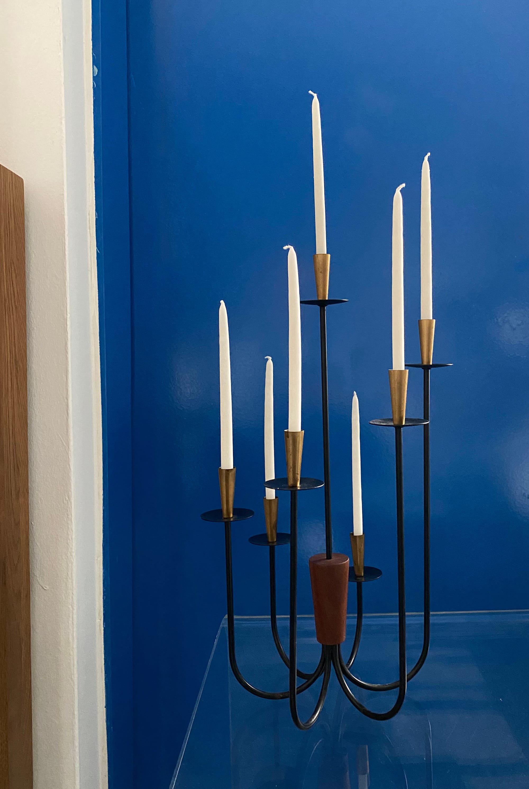 Mid-century candle holder with seven arms holding slender white tapers.