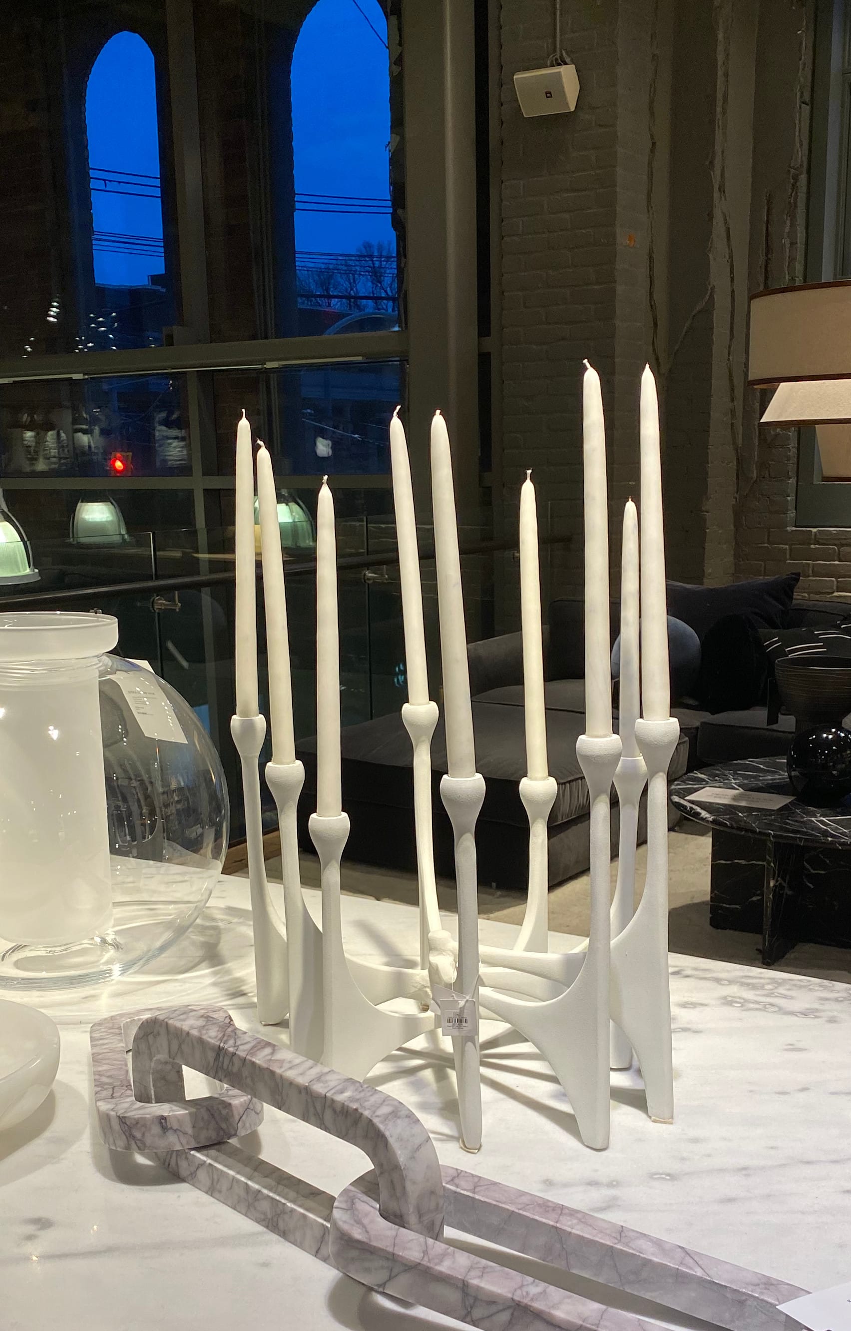 Nine-armed white candelabra holding white unlit candles.