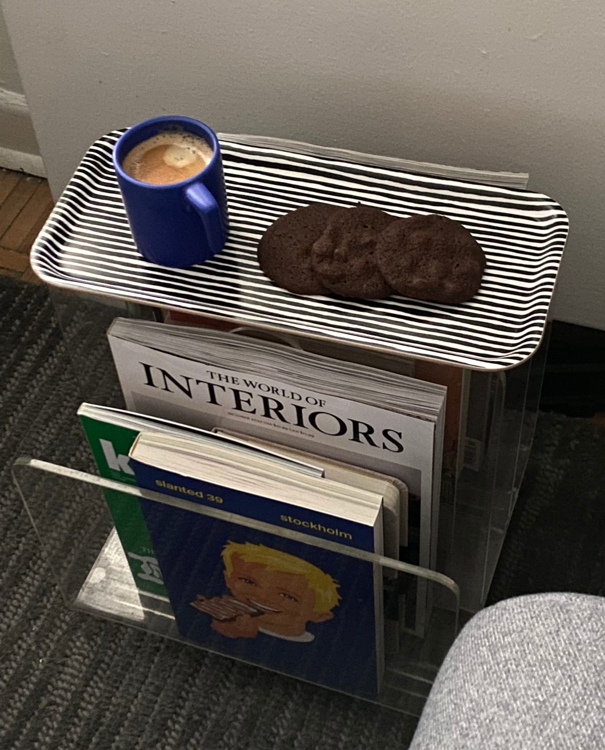 Tray resting on a magazine holder, with a coffee and cookies on it.