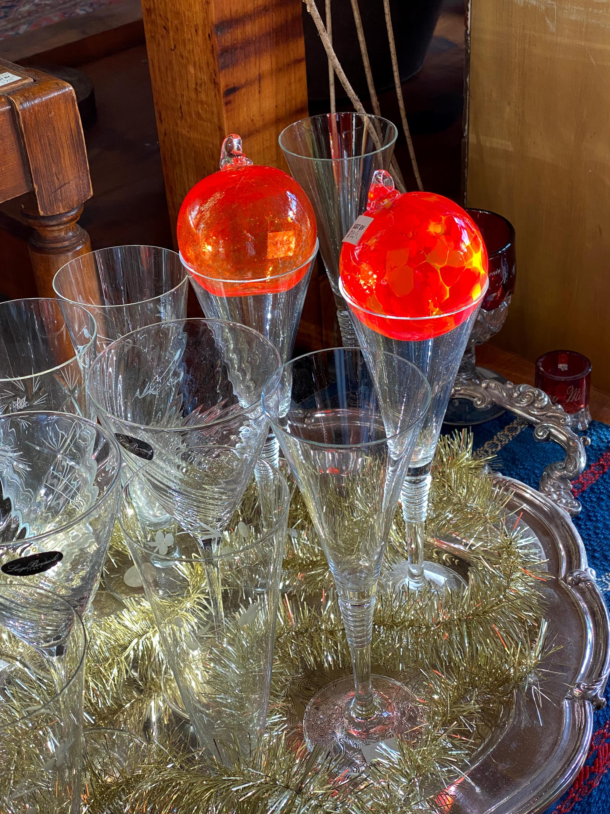 Two red ornaments resting in the mouths of champagne glasses.