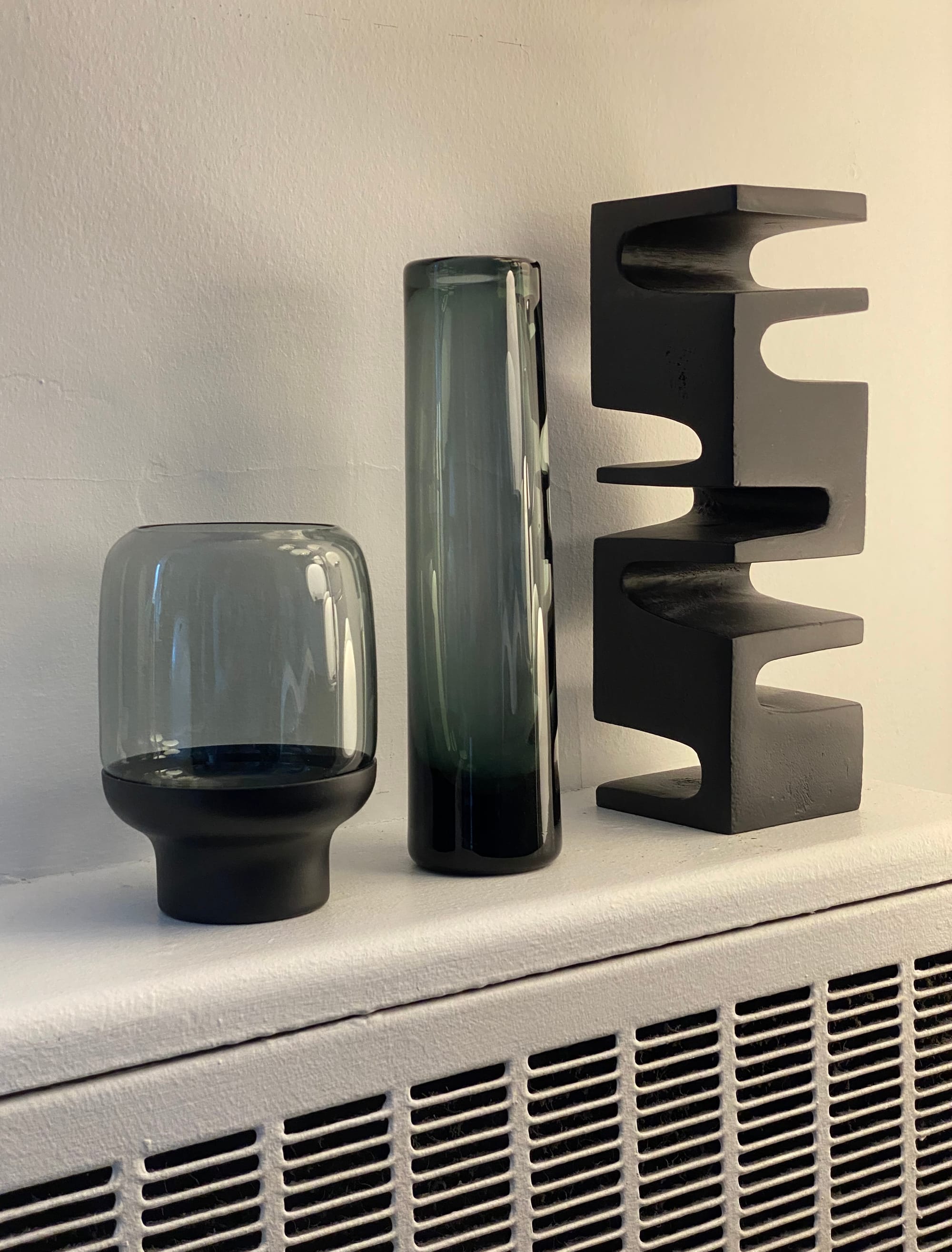 Candle holder, vase, and small sculpture, all resting on a radiator.