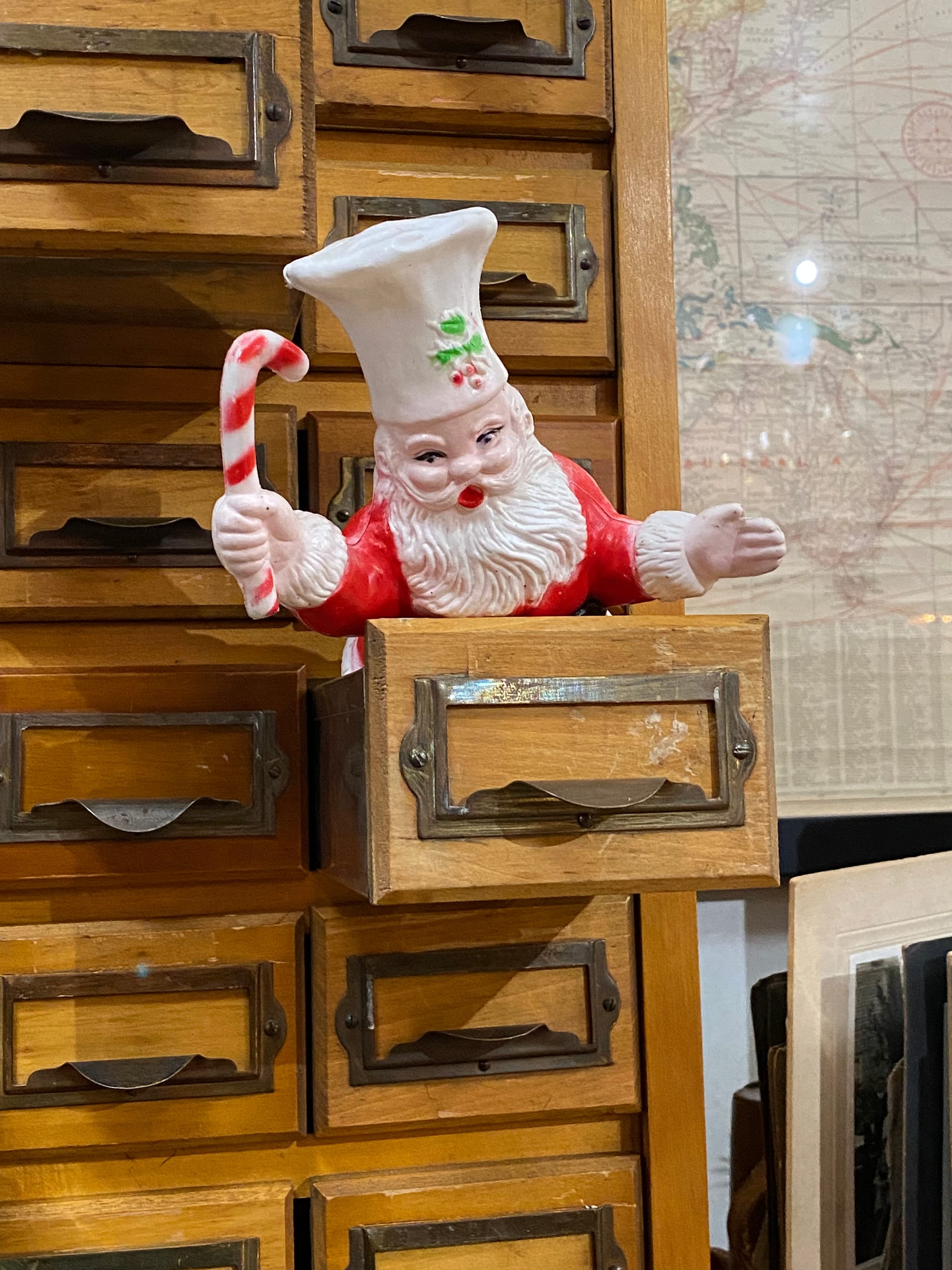 Plastic Santa figurine popping out of a wooden drawer.