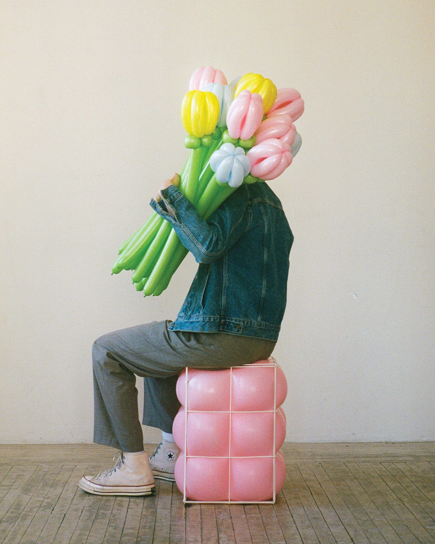 Seated man holding a bouquet of tulips made from balloons.