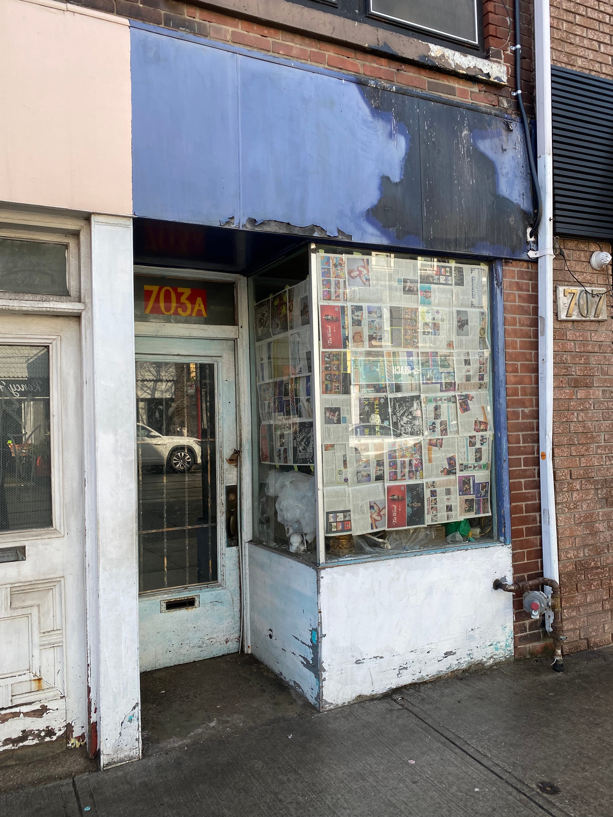 Odds & Ends shop with signage removed and newspapers over the window.