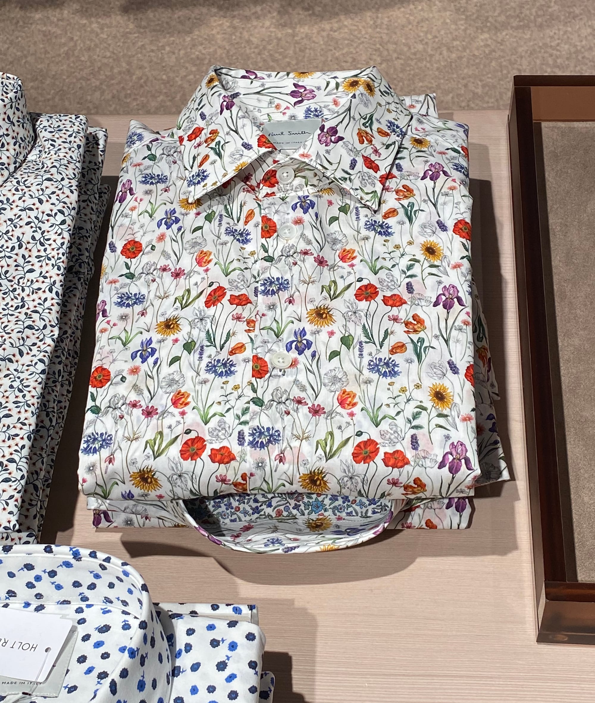 Neatly folded Paul Smith shirt densely patterned with flowers.