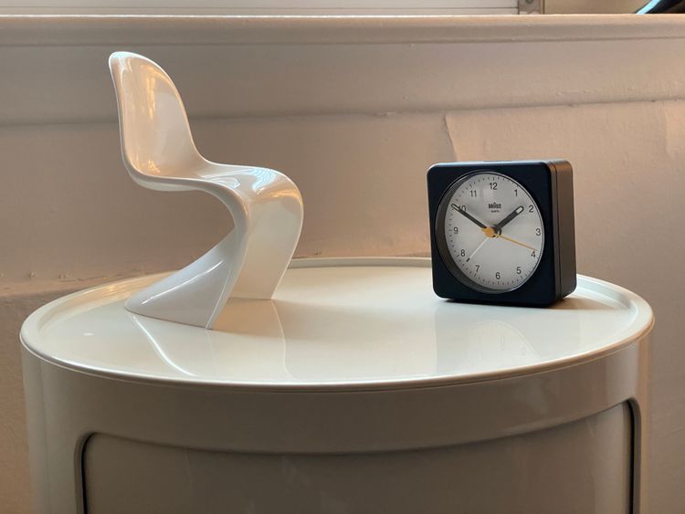 Braun alarm clock and a miniature Panton chair together on a side table.