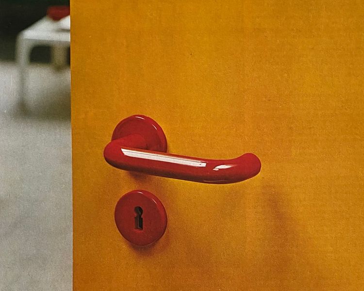 Yellow door with red door handle.