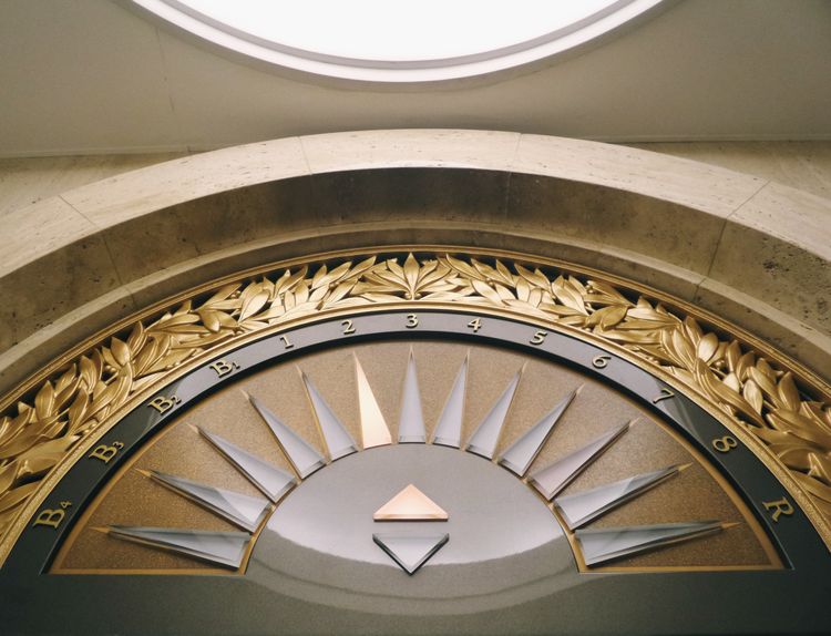 Ornate fixture above an elevator entrance indicating what floor the elevator is on.