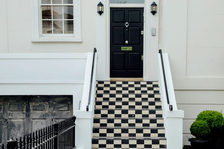 Stylish exterior of a home with a black and white patterned staircase leading to a black front door.