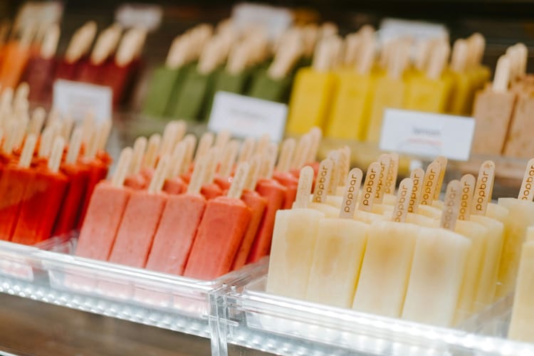 Popsicles of various colours arranged in trays.