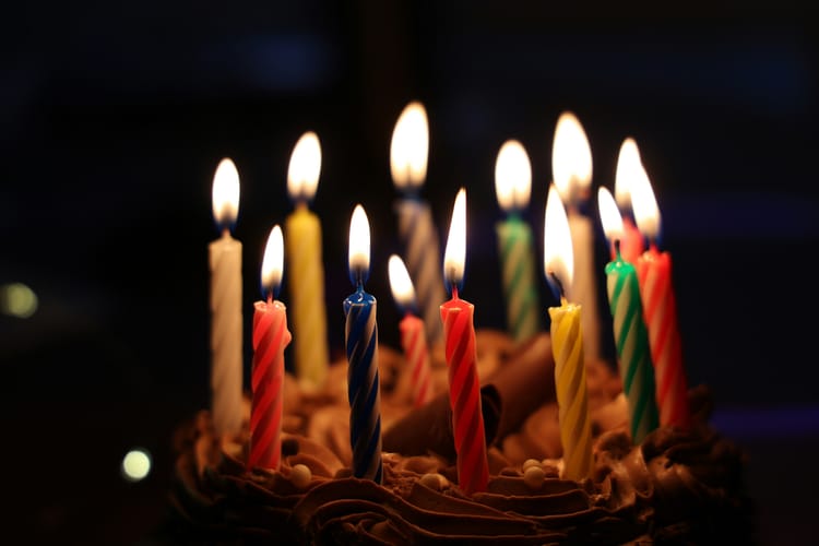 Close up of birthday candles on a small cake in a dark room.