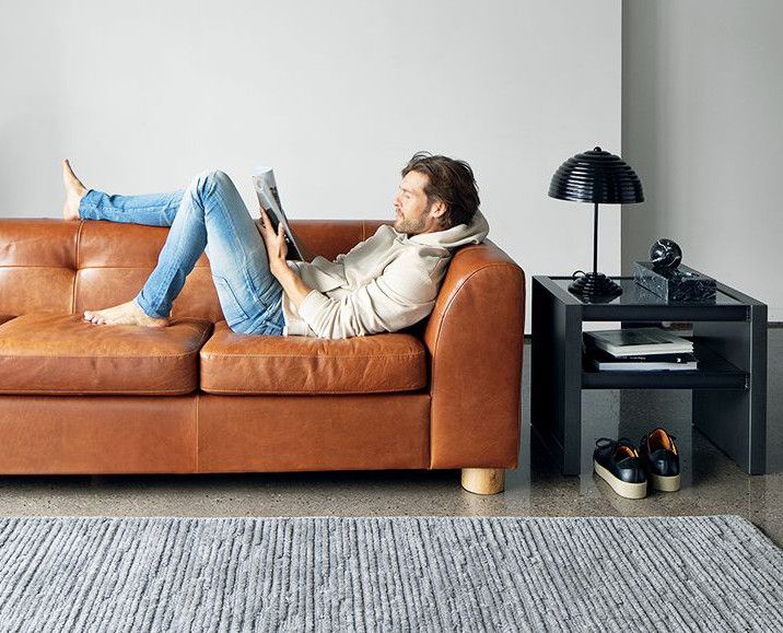 man relaxing on leather sofa riding a magazine