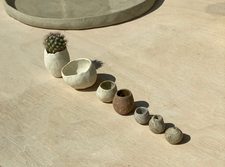 Seven tiny ceramic pots in a line from biggest to smallest