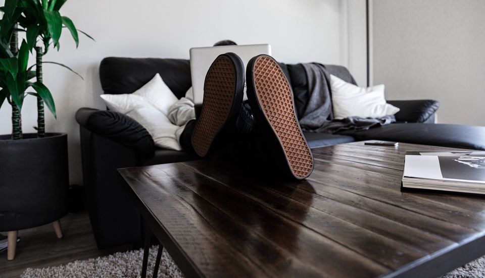 Close-up view of a coffee table, with the sneaker soles of a lounging figure the centre of attention.