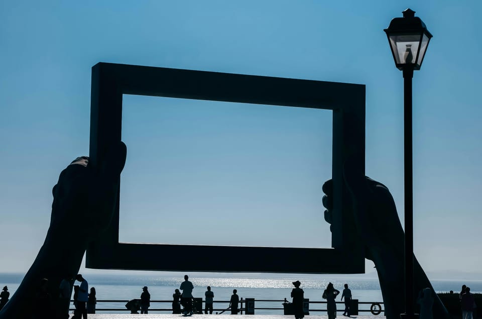 Hands holding empty picture frame to the sky.