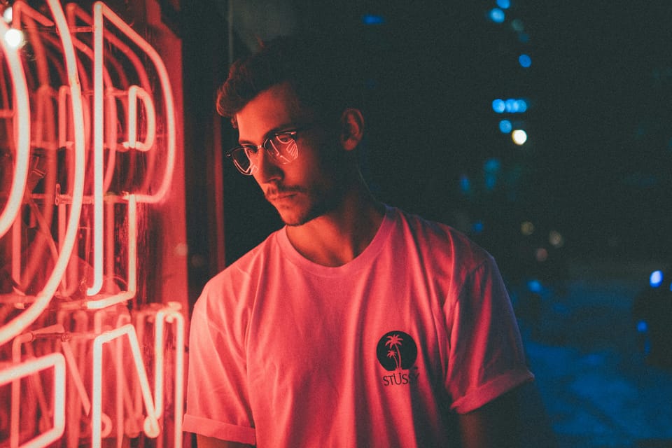 Man looking into a store window with a bright neon OPEN sign.