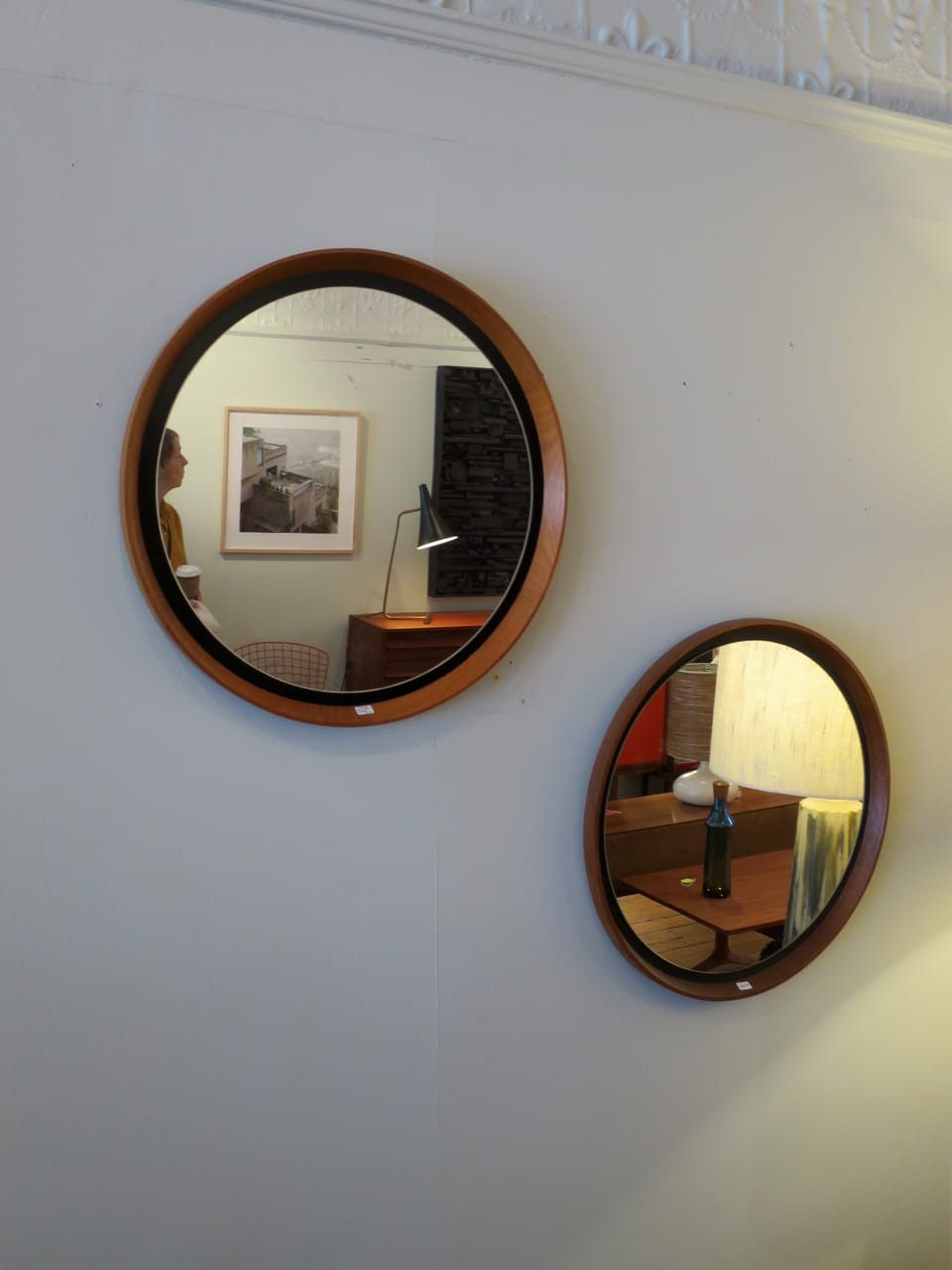 Two round mirrors on a wall showing reflections of the inabstracto merchandise.